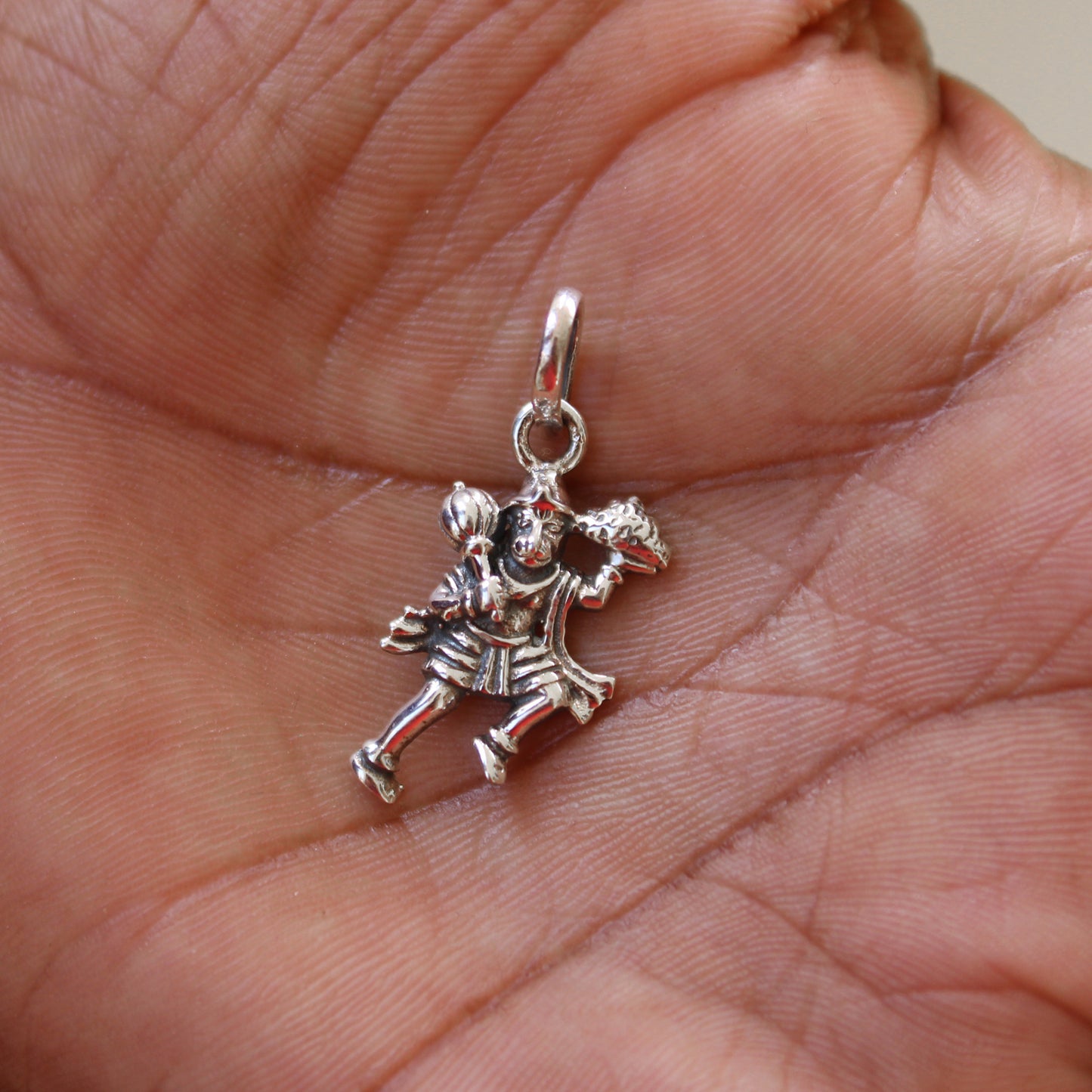 Silver clown charm held in a hand